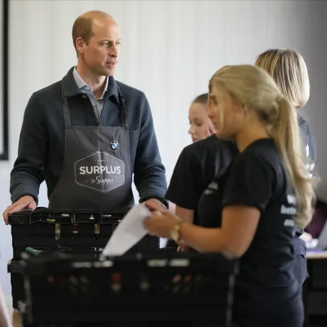 The Prince of Wales helps to pack crates of food at food redistribution charity Surplus to Supper