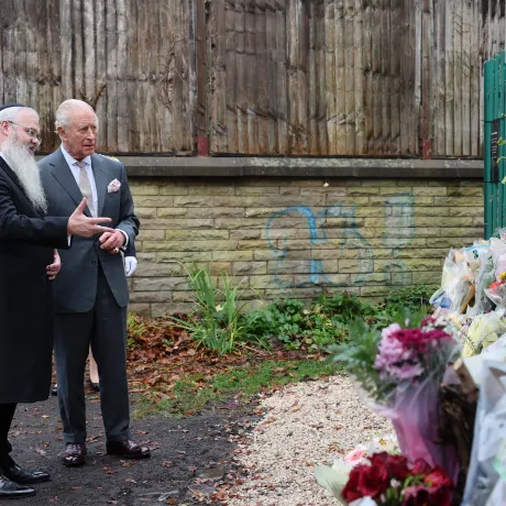 The King, alongside Rabbi Daniel Walker, look at floral tributes 