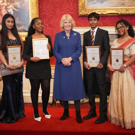 The Queen smiles alongside winners and runners-up of The Queen's Commonwealth Essay Competition