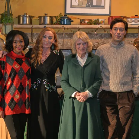 The Queen smiles alongside members of the Rivals cast