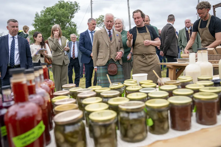 King Charles speaks to a Scottish business owner. Jars of bottled product are in the forefront