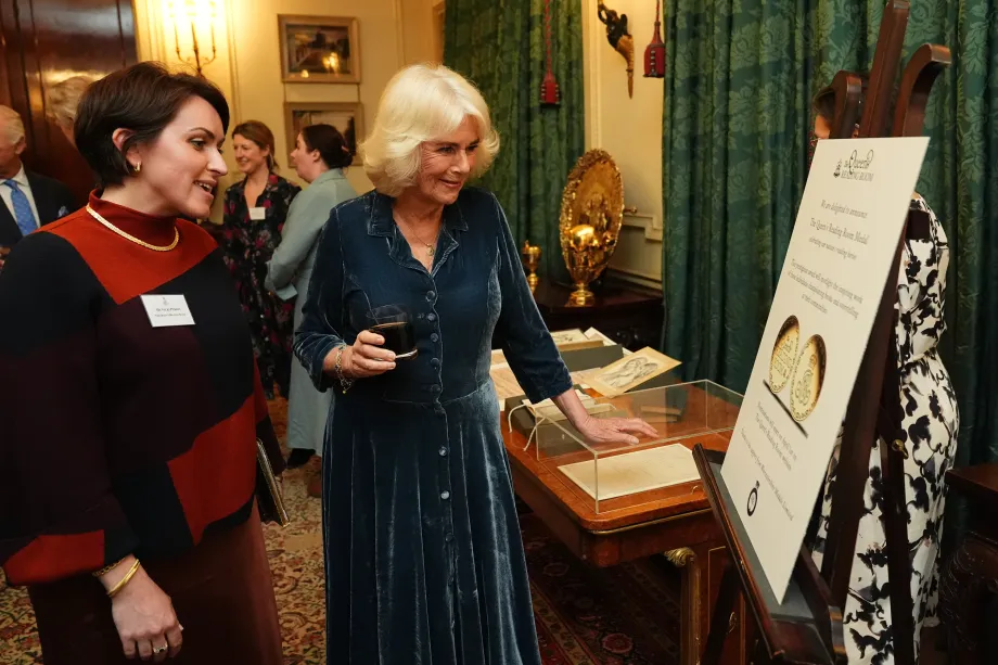The Queen looks at the Queen's Reading Room Medal
