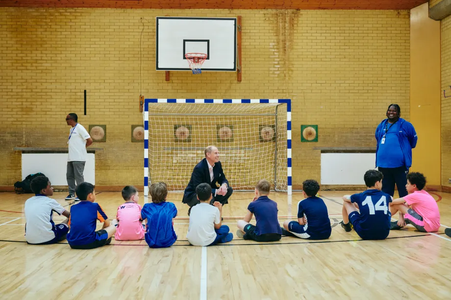 The Duke of Edinburgh speaking to children in a sports hall