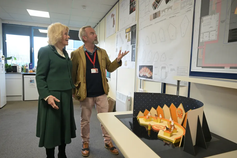 The Queen views models and plans of the film stages during a visit to the Rivals set