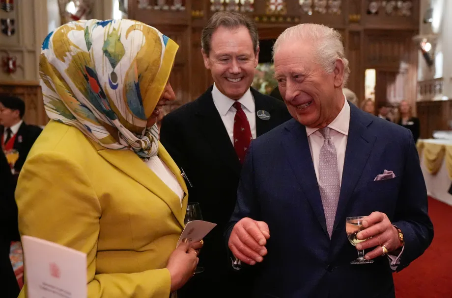 The King smiles with a guest during a reception at Windsor Castle